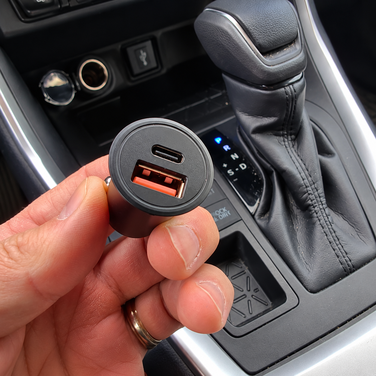Dual-port 12V car charger held inside a vehicle console