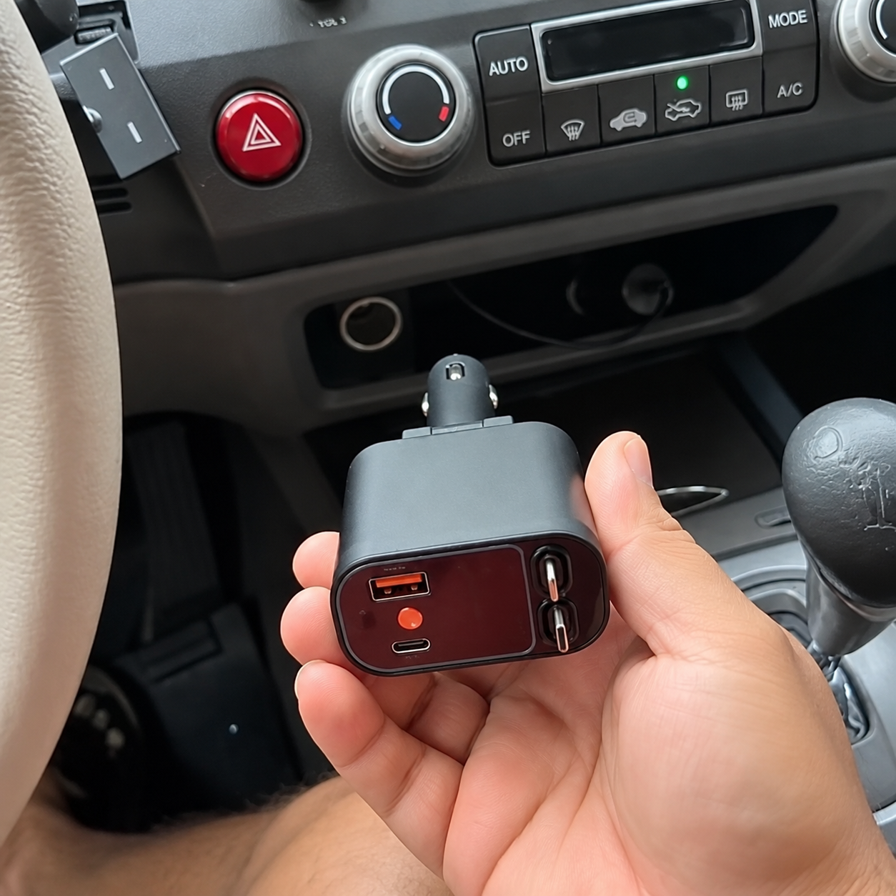 Multi-port 12V car charger held near a vehicle socket